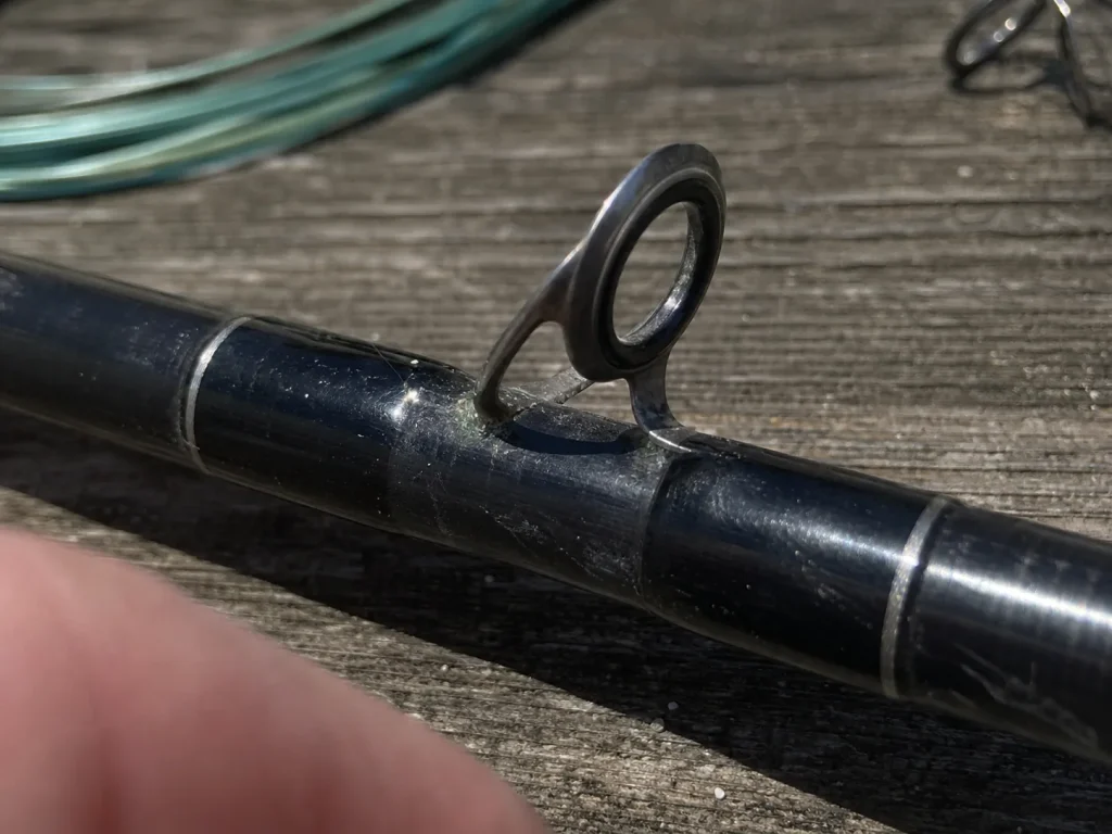 Close-up of a surf rod guide showing insert and frame corrosion on the blank