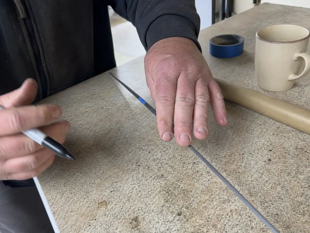 Hands rolling a taped rod blank on a table to find the spine by the compression method