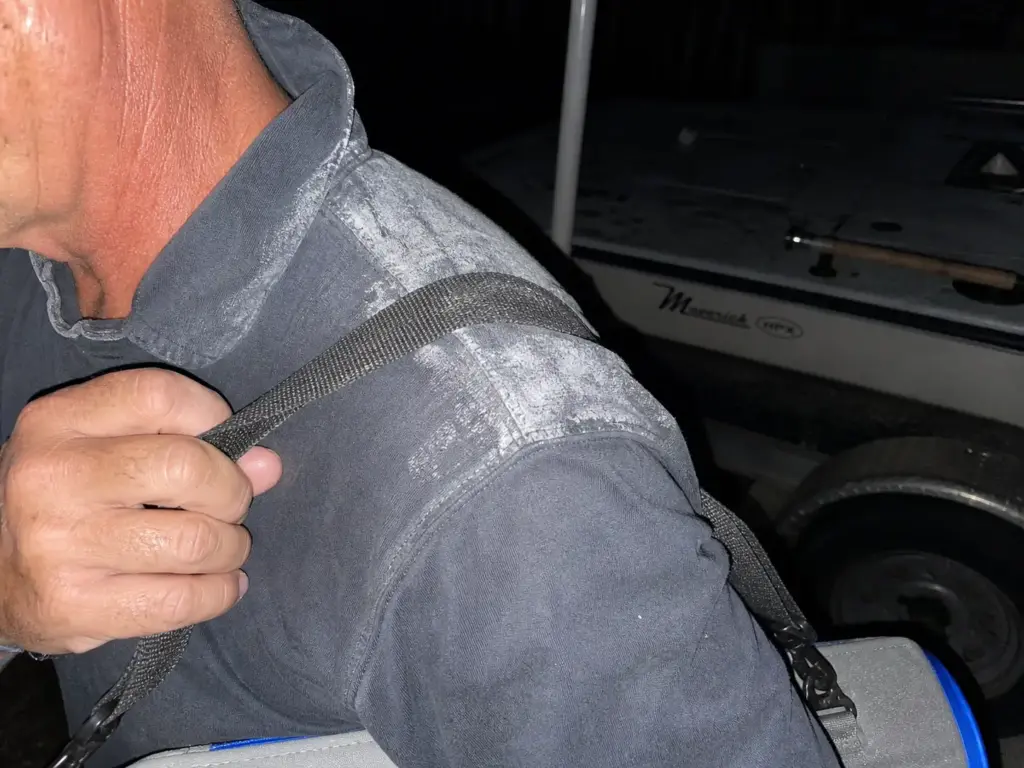 Salt-stiffened shoulder of a sun shirt worn under a strap, photographed with flash at the end of a day