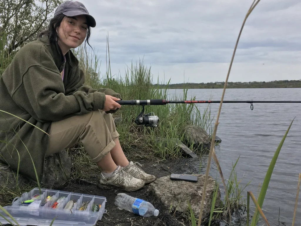 Beginner angler fishing from a grey lake bank with a composite spinning combo, relaxed and unhurried