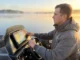 Avoid Dead Zones: Fish Finder Transducer Cone Geometry Professional angler in a bass boat cockpit at dawn, looking focused, with a high-tech Lowrance fish finder screen glowing in the foreground.