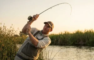 Best Carp Fishing Rods: Range & Sensitivity An angler performing a powerful overhead cast with a carp rod at sunset by a lake.
