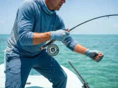 Best Fishing Gloves: Sun, Cold & Handling Close-up of an angler's gloved hands gripping a fishing rod tightly under bright sun.