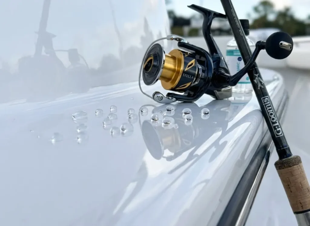 Water beading on a ceramic coated boat hull with the reflection of a Shimano Stella reel and G. Loomis rod visible in the shine.