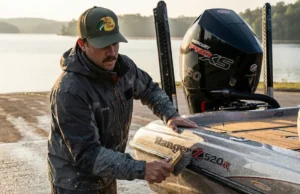 Cleaning Boat Hulls to Stop Invasives: A Full Gear Guide Angler in Simms gear cleaning the hull of a Ranger bass boat with a Mercury outboard at a boat ramp.