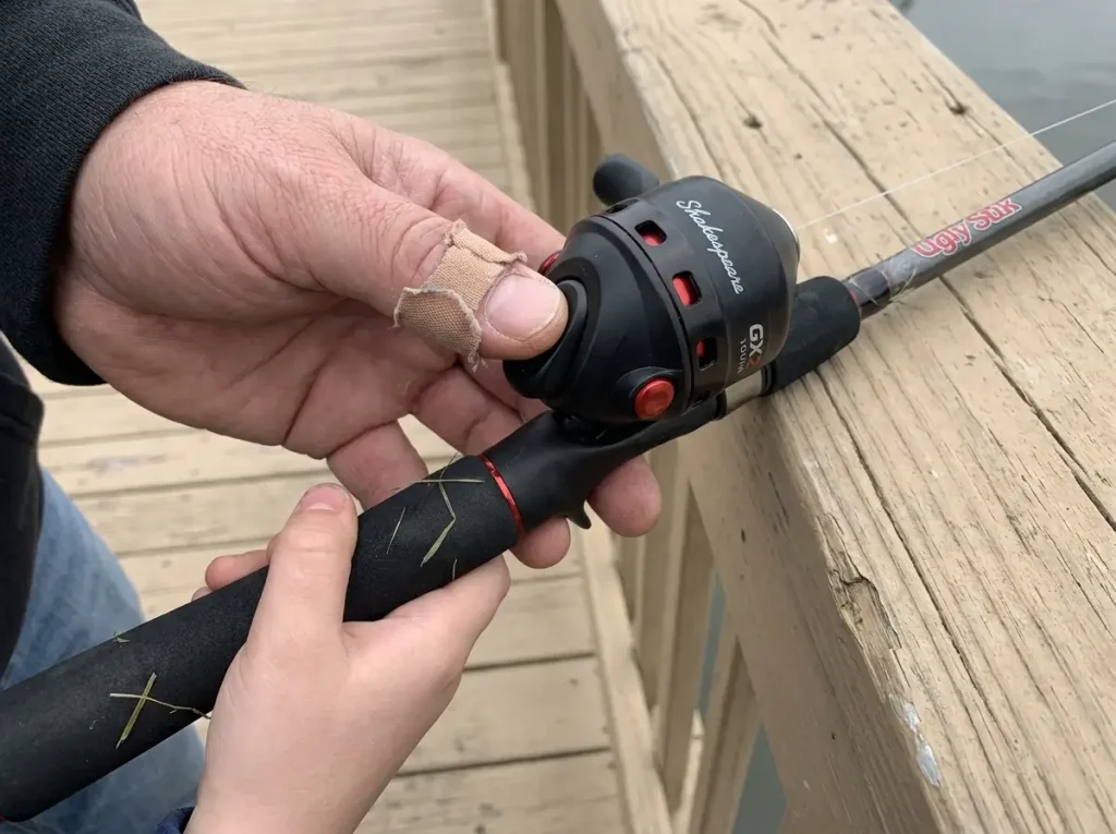 Close-up of a closed-face push-button spincast reel on a tangle-free kids fishing pole