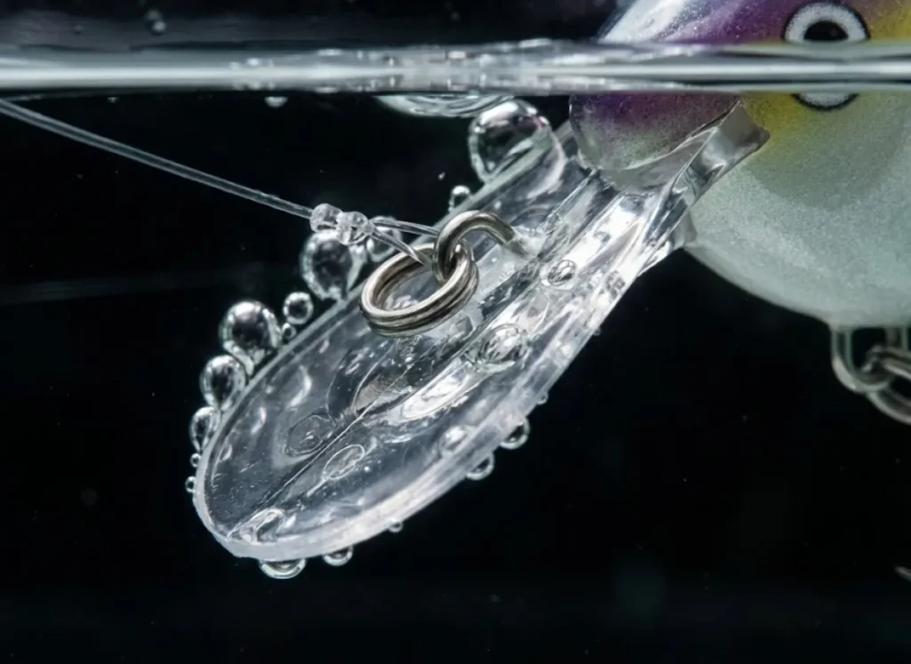 Macro photography of a crankbait underwater showing the bill angle and line tie mechanics causing a hydrodynamic blowout.