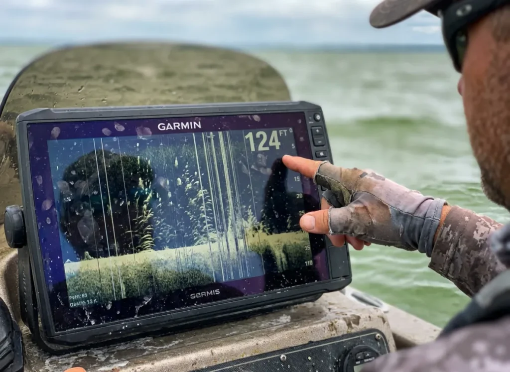Angler pointing at a fish finder screen showing sonar clutter and interference caused by mixing water layers.