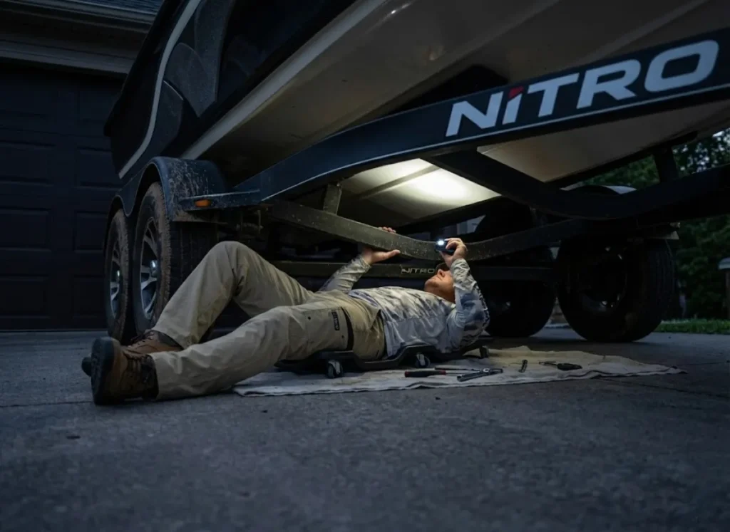 Angler using a Black Diamond headlamp to inspect the underside of a Nitro boat trailer.