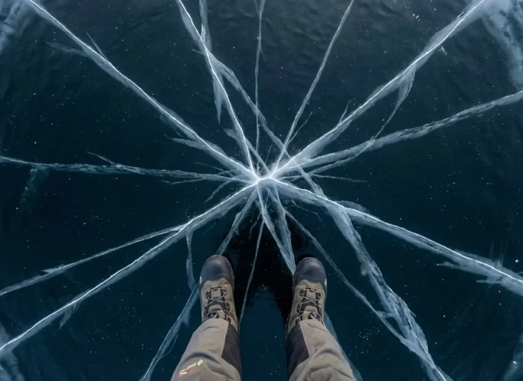 Top down view of radial cracks in lake ice, viewed from the perspective of an angler wearing Korkers boots.