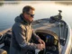 Metabolic Strike Guide: Fishing Dissolved Oxygen Levels Professional angler in Simms gear scanning a calm lake from a bass boat console at sunrise, cinematic lighting.