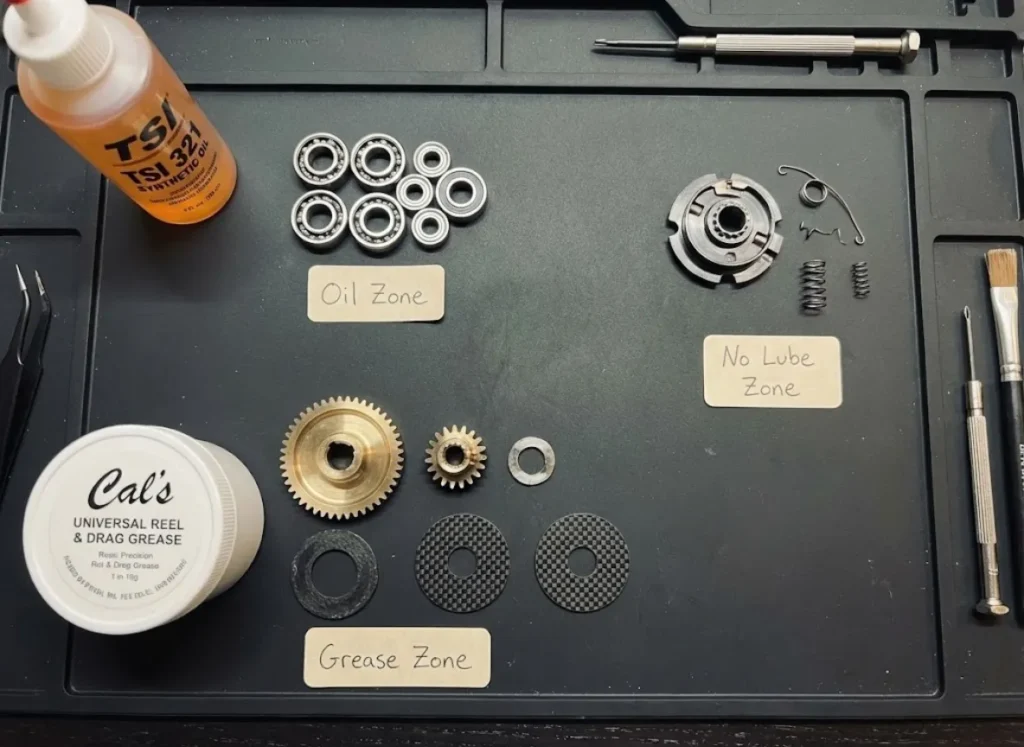 Disassembled Daiwa Saltiga reel parts organized by lubrication zones with TSI 321 oil and Cal's grease.