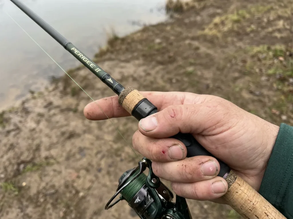 Close-up of hands sensing a bite through a graphite rod blank, showing modulus stiffness