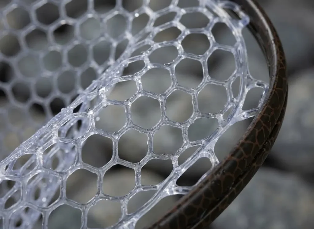 Close-up detail of a hydrophobic rubber fishing net mesh with water beading on the surface, designed to protect fish slime coats.