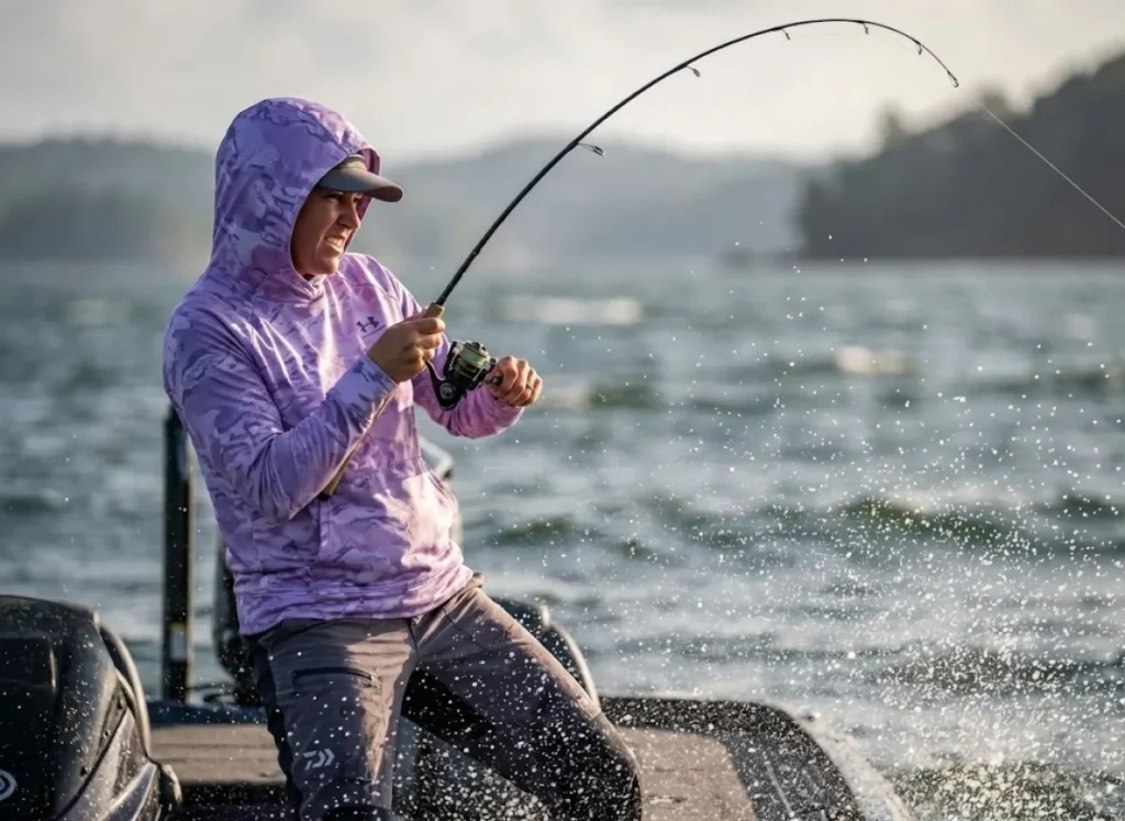Female angler in Under Armour gear setting the hook with a Daiwa rod.