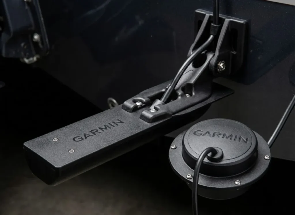 Macro photography close-up of a Garmin fish finder transducer, highlighting the matte black texture and hydrodynamic design.