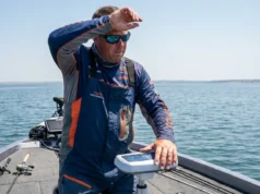 Thermoclines Explained: Fishing Depth & Sonar Guide Angler on a boat in summer heat studying fish finder sonar for deep water layers.