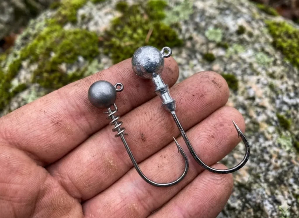 Close-up comparison of a small tungsten jighead versus a larger lead jighead held in a hand.