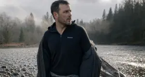 Merino vs Synthetic Fishing Base Layer System Angler in a merino base layer under an open wading jacket at a cold river before fishing