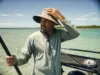 Fishing Hat Sun Protection Features Guides Check First Angler in a wide-brim UPF hat checking fishing hat sun protection features on shallow water
