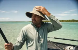Fishing Hat Sun Protection Features Guides Check First Angler in a wide-brim UPF hat checking fishing hat sun protection features on shallow water