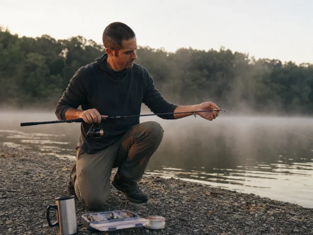 0-fishing-rod-length-hero-bank-first-light Angler rigging a 7-foot rod at first light, matching rod length to the fishing situation on a quiet reservoir bank