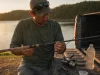 Why Fishing Rod Labels Lie and How to Read Them Angler decoding the printed specs on a fishing rod blank above the cork handle at a lakeside tailgate