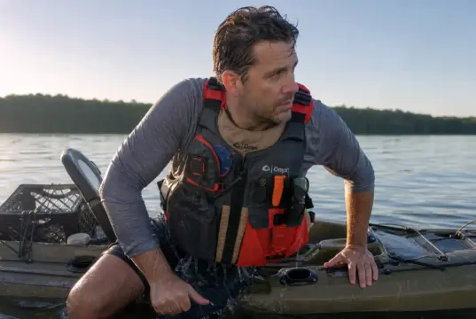 5 Kayak Reentry Mistakes That Keep You in the Water Angler in a kayak fishing PFD beside his sit-on-top after a deep water kayak reentry drill