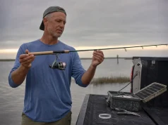 Rod Guide Materials and Why Most Anglers Overpay Angler sighting down a spinning rod to inspect the guide train at the tailgate after a morning tide