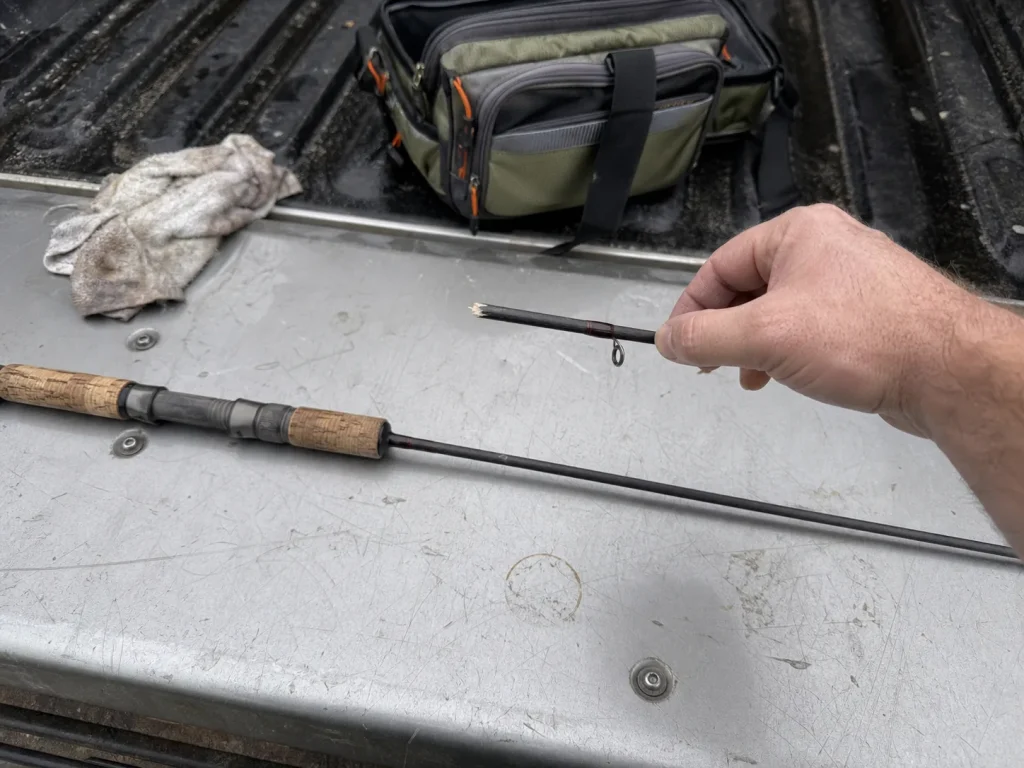 A snapped fishing rod in two pieces on a truck tailgate, a common warranty claim scene