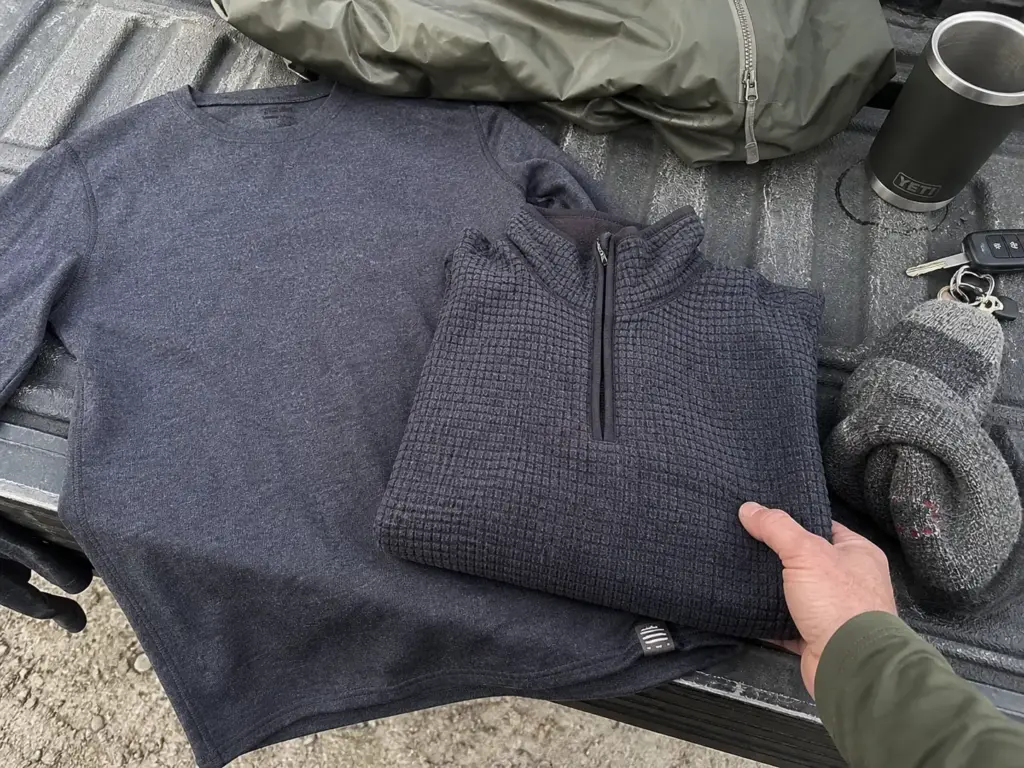 Base layer, fleece mid layer and shell laid out on a tailgate showing a fishing layering system