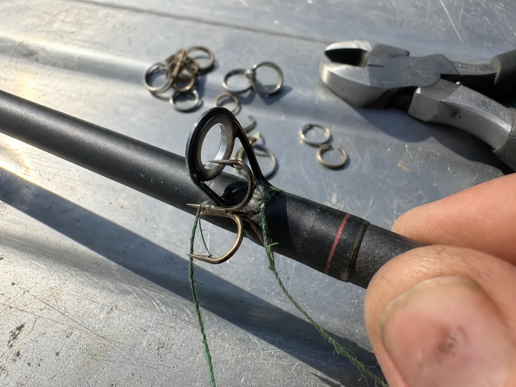 Close-up of a fishing hook resting wrong against a rod guide instead of the hook keeper, chipping the insert