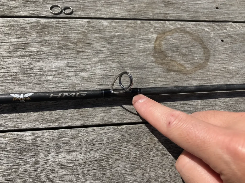 Close-up of a spinning rod stripper guide showing the ceramic ring seated in its titanium frame
