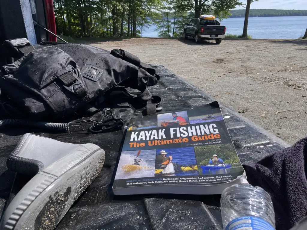 Kayak fishing guide book and wet practice gear laid out on a truck tailgate after a self-rescue session