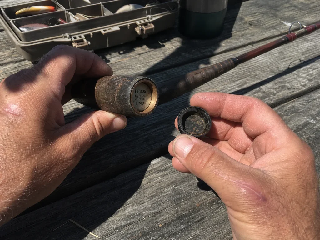 Angler popping the butt cap off an old rod to find a hidden model number when the outside label is worn off