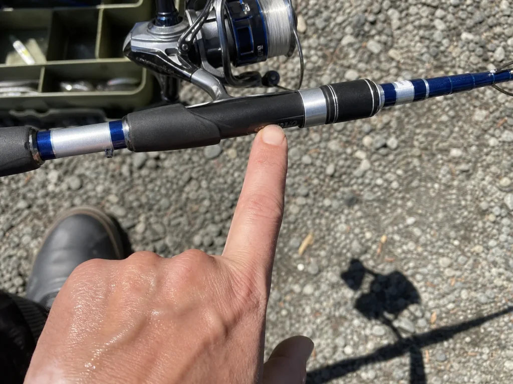 Close-up of a finger under the reel seat finding the balance point on a spinning rod