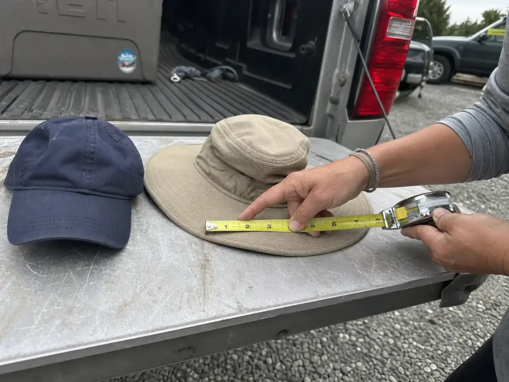 Tape measure across a fishing hat brim next to a ball cap showing brim width difference