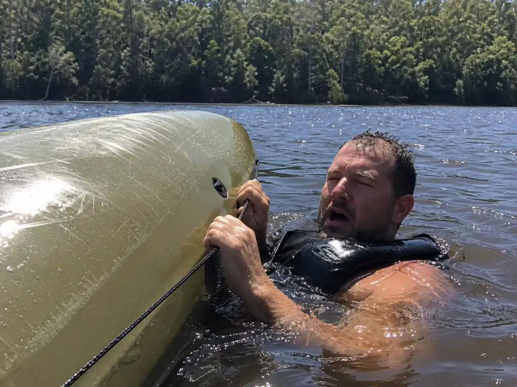 Kayak angler in the water holding his overturned kayak's deck line in the first seconds after a capsize