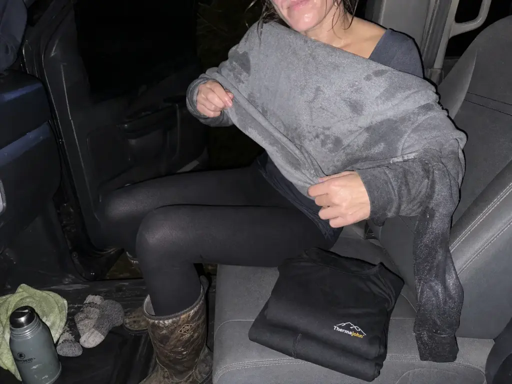 Soaked cotton hoodie pulled off in a truck cab next to a dry thermal base layer set