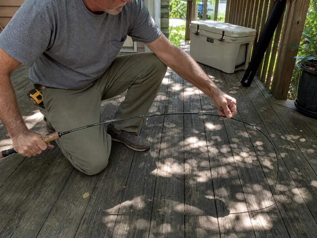 Angler pressing a rod tip against the floor in the floor-flex test to read where the blank bends
