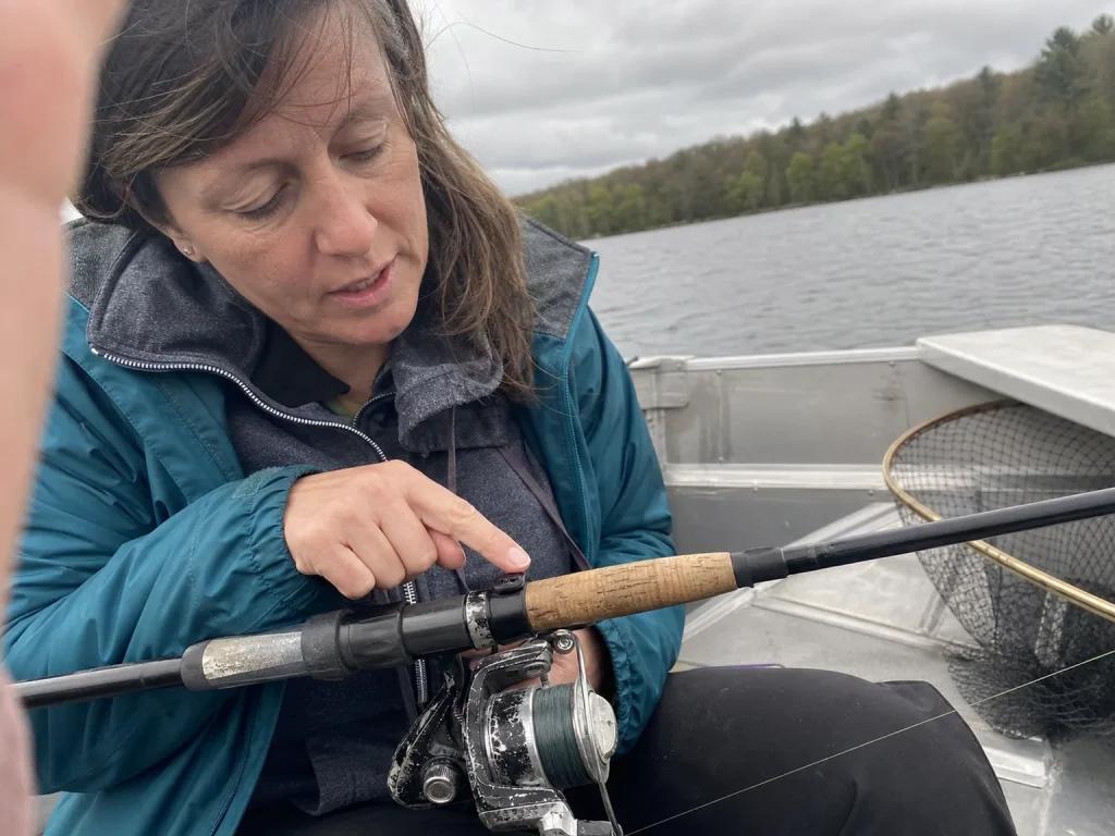 Angler pointing to the hook keeper position above the reel seat on a spinning rod to show correct placement