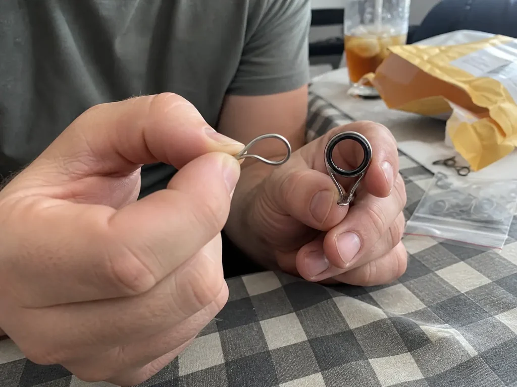 A ringless nickel-titanium rod guide being flexed between finger and thumb to show shape memory