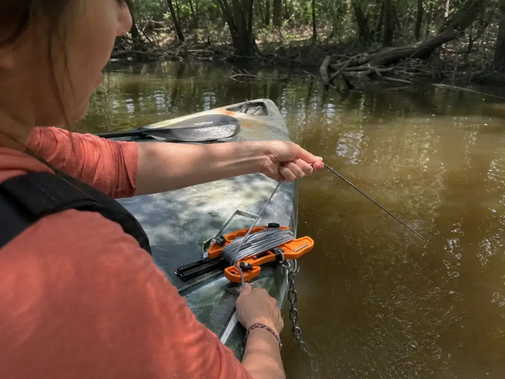 Angler paying out measured anchor line from a track-mounted reel to set the scope ratio