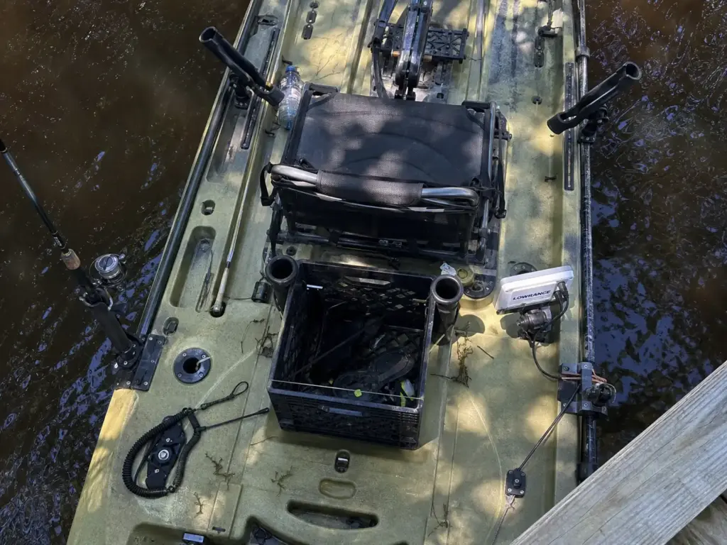 Overhead view of a fully rigged fishing kayak deck showing rod holders, crate and trolley line snag points