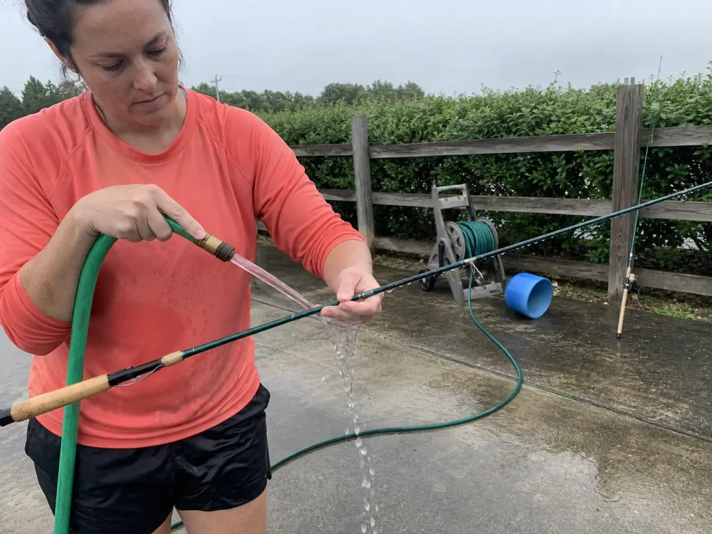Rinsing salt from the guide frames of an inshore spinning rod with fresh water after a trip