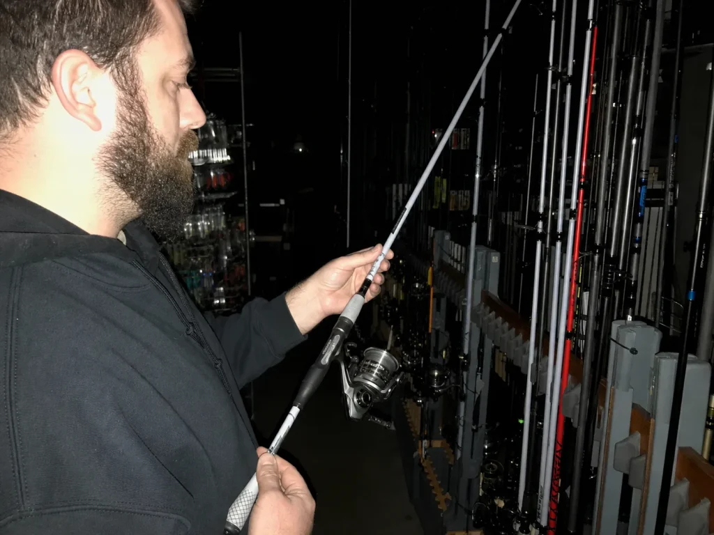 Angler comparing rod lengths on a tackle shop rack, the aisle decision the length matrix solves
