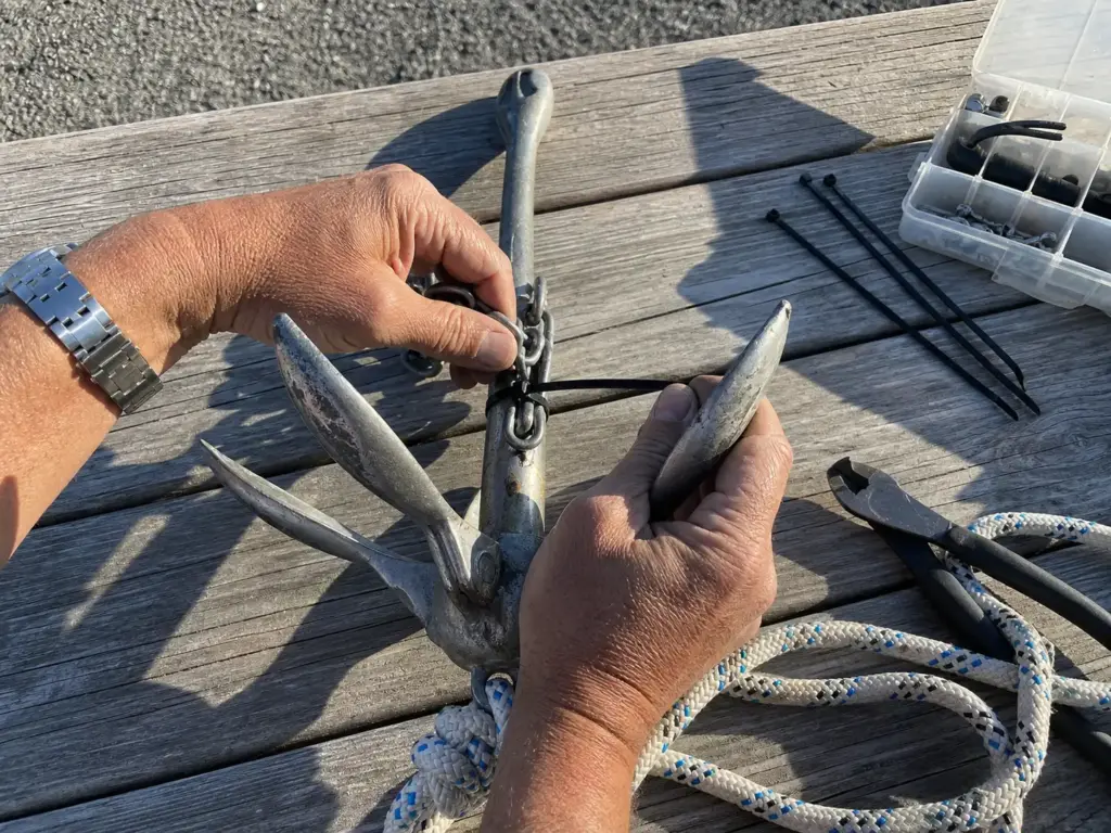 Hands tying a breakaway weak link zip tie on a kayak grapnel anchor shank