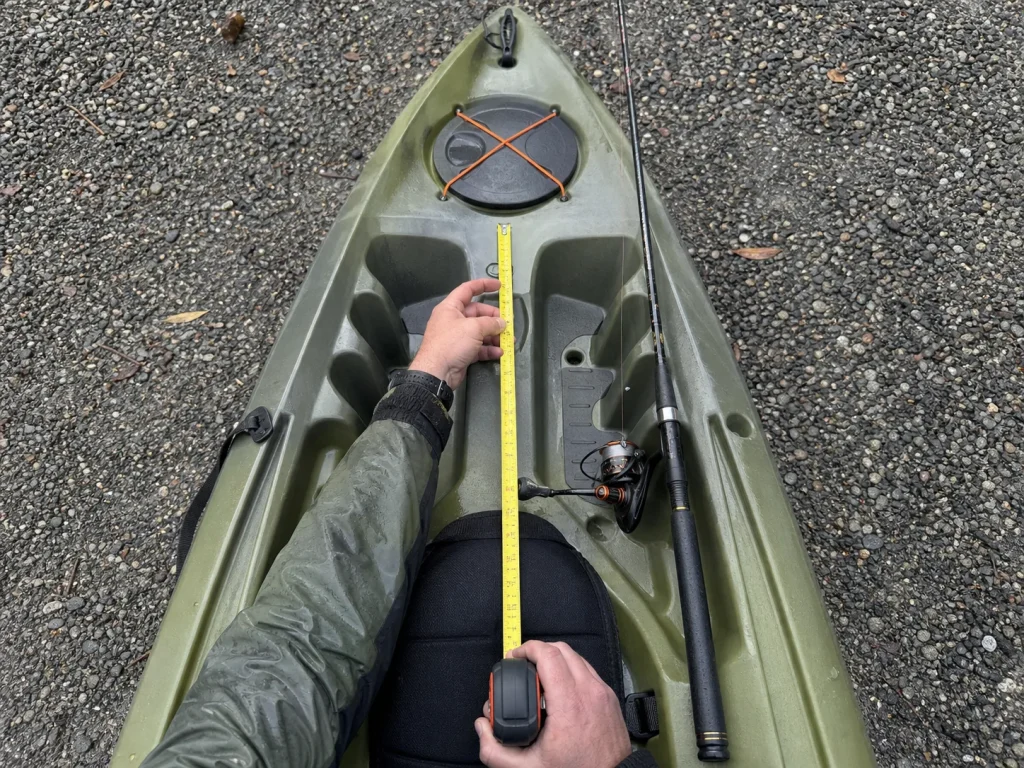 Measuring a kayak seat-to-bow distance with a tape to pick the right fishing rod length