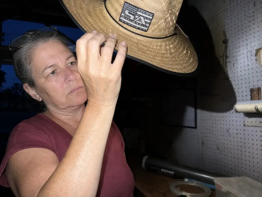Sun-faded straw fishing hat held up to a light showing worn weave and UPF degradation