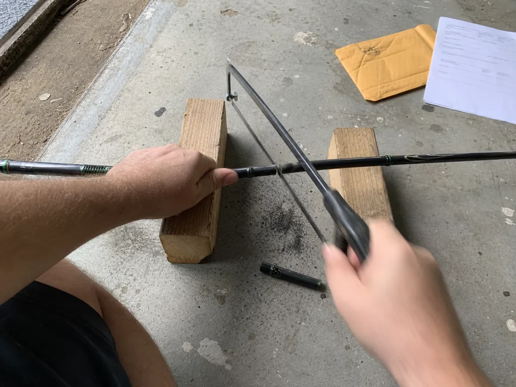 Hands cutting the logo section from a broken rod blank to mail in for a replacement program